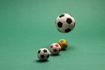 miniature toy football soccer ball black and white colour over green background copy text space concept