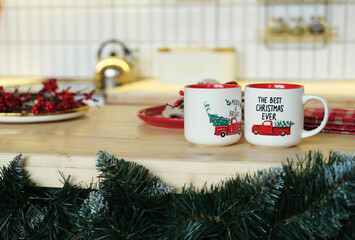 Christmas kitchen decor. 2 cups with a festive pattern and an inscription are on the table