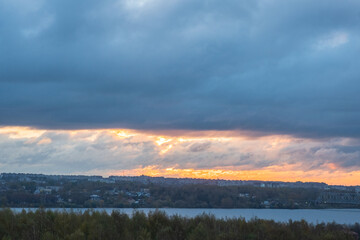 Sunrise over the city across the river. Panoramic View. Colorful sky with sun in clouds.