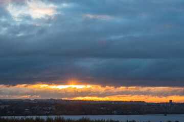 Sunrise over the city across the river. Panoramic View. Colorful sky with sun in clouds.