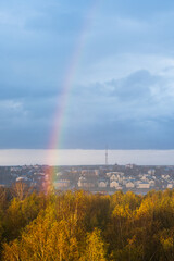 Rainbow after the rain over the river against the backdrop of the city. Blue sky, yellow trees.Beauty in nature.
