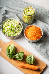 The preparation process fermentation preservation Sauerkraut. The best natural probiotic.Ingredients harvesting for gray cabbage soup: young green cabbage and carrots  on wooden board.