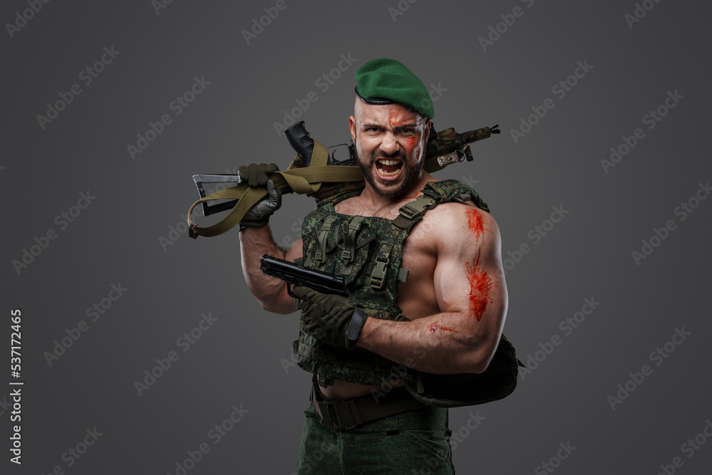 Wall mural Shot of screaming russian soldier dressed in camouflage uniform holding rifle and pistol.