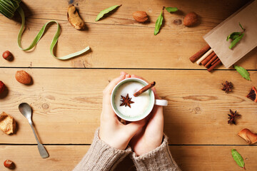 Female hand holding a cup with Indian Masala chai tea. Traditional Indian hot drink with milk and...