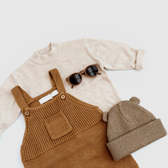Knitted jumpsuit, sweater, warm hat, sunglasses on white background. Set of baby fashion clothes...