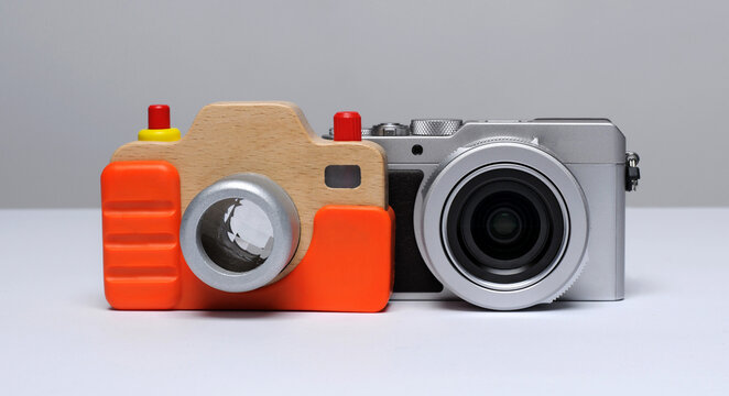 A wooden camera, an educational toy on the background of a compact modern digital camera ... 