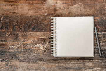 Notebook or sketchbook with pen mockup. Top view on blank brown notebook on old brown background. Mockup blank notebook and pen on old rustic wooden table. top view. copy space
