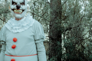 evil clown in motion walking in the woods at dusk