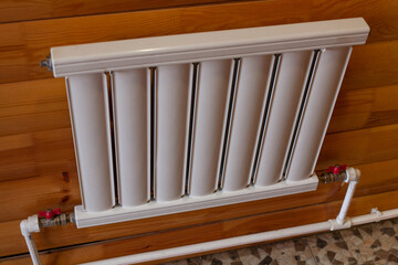 Radiator of water heating on a wooden wall close-up