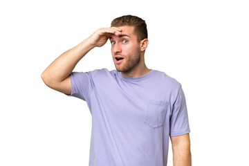 Fototapeta premium Young handsome caucasian man isolated on green chroma background doing surprise gesture while looking to the side