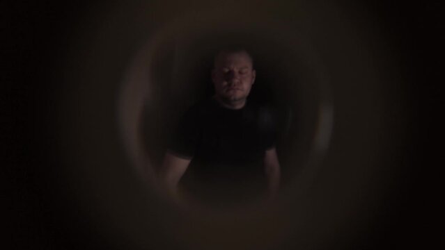 A disgruntled angry neighbor stands on the stairwell and knocks on the door of the apartment. View from the peephole. Close-up
