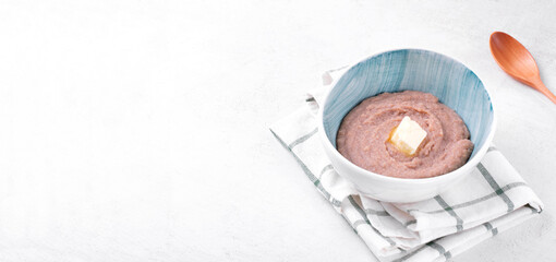 Creamy farro porridge with butter served in bowl. Web banner with healthy breakfast meal. Copy space
