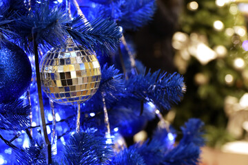 Christmas tree with blue and mirror balls in a shopping mall on background of blurred festive lights. New Year toys and decorations, winter holidays	