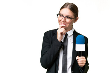 Young TV presenter caucasian woman  over isolated background thinking an idea and looking side