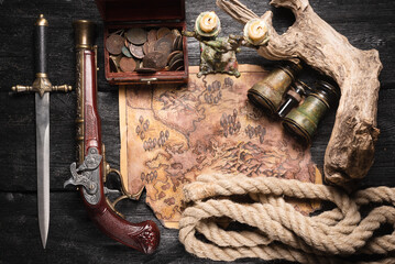 Ancient pirate treasure map and musket gun on the table top view concept background.