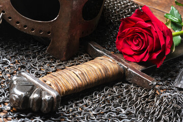 Red rose flower and knight sword on the black table background close up.