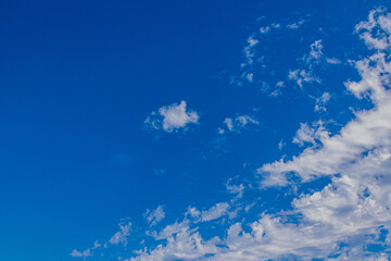 Fototapeta na wymiar natural blue sky on a sunny day with white wispy clouds background
