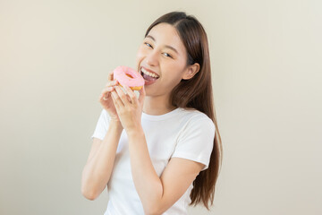 Portrait of attractive beautiful girl, pretty asian young teenage woman holding pink donut, doughnut, emotion enjoy sweet. Dieting, diet for loss weight to slim. Isolated white background, copy space.