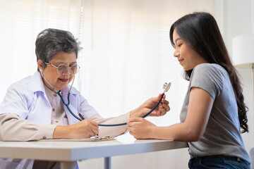 Mature, senior asian physician, psychiatrist, general woman doctor consulting concerned with young...