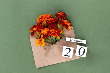 October 20. Bouquet of orange flower in craft envelope and calendar date on green background. Minimal concept Hello fall. Template for your design, greeting card