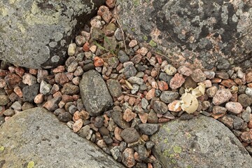 Small rocks surrounded by big rocks at seashore.
