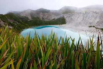 A stunning turquoise water lake in the volcanic crater at summit of Mount Balbi, hiking in the...