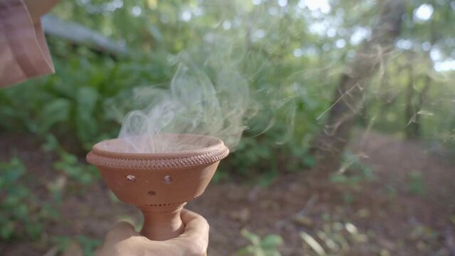 Close up of Asian female hands infusing sambrani Benzoin for air purification in Yoga forest retreat at Goa India