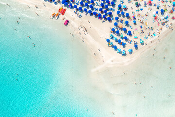 Top view of beautiful sandy beach with turquoise sea water and colorful umbrellas, Islands of Sardinia in Italy, aerial drone shot