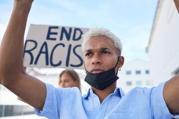End racism sign, poster and black man protest in face mask, cardboard in urban street for...