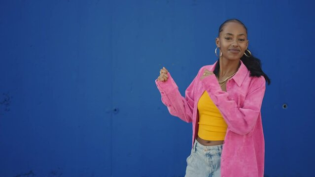 Cinematic footage of a professional hip hop female dancer outddor . Teenager girl with fashionable clothes dancing in a colored modern area of the city