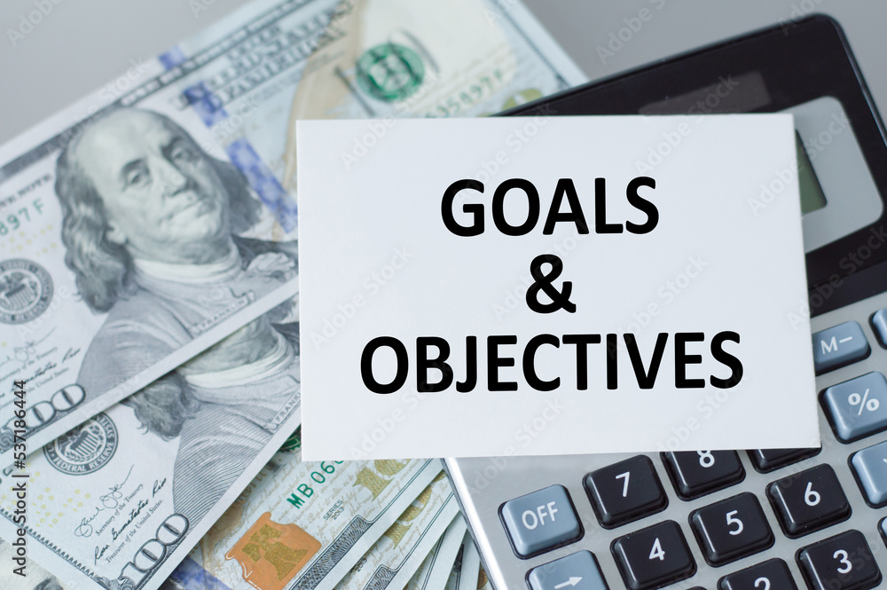 Poster goals and objectives, text on a card on the background of the calculator and money on the table