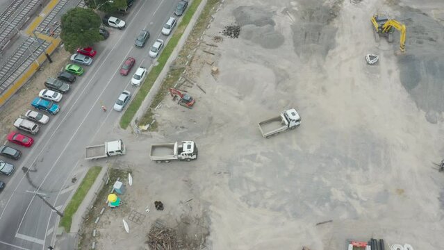 Three empty loading trucks driving onto hardstand where excavator waits for them to move into position for transfer.