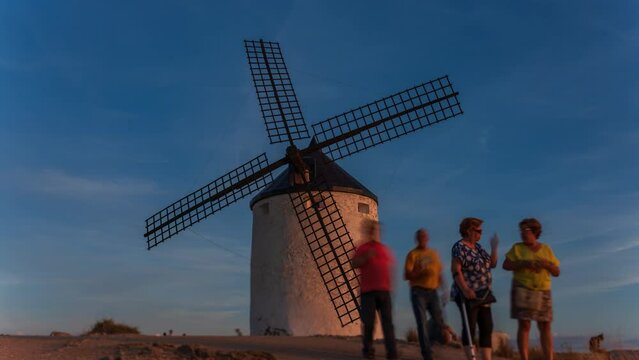 Awe old windmill with blurred people at sunset