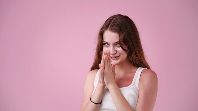 4k video of woman rubbing her hands on pink background.