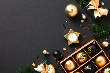 Luxury Christmas flat lay composition. Gold baubles, Xmas ornaments, gift boxes, fir branches on black background. Christmas or New Year celebration concept.
