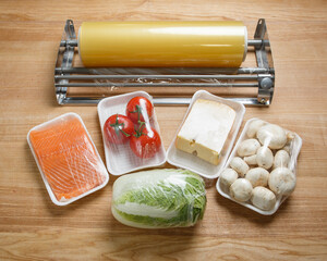 Tomatoes, mushrooms, cheese, salmon fillets and Chinese cabbage are wrapped in cling film.