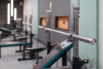 Close up of empty barbell bar without plates on rack in gym club.