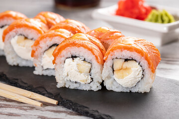 Set of Philadelphia sushi on black concrete plate on table.