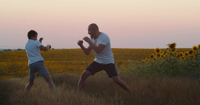 A father and his little son practice boxing in the field