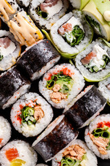 Close-up view of various sushi rolls with different fillings on black metal slate.