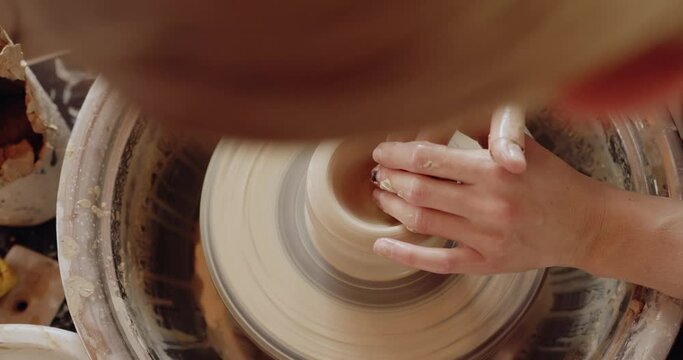 Close up of female artist hands working with clay on pottery wheel