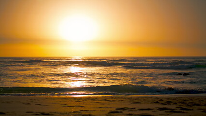 Obraz premium Sunrise landscape Ursa beach with orange sun reflecting Atlantic ocean surface