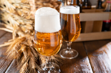 Glass of light craft beer on a wooden table. Beer is poured into a glass with foam and bubbles. Vertical. for social media or advertising. beer texture. 