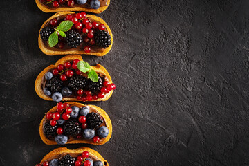 Bread toast with chocolate paste and berries on black background