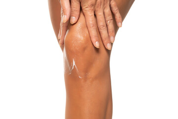 Woman applying moisturizer cream on the knee