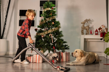 Little boy using vacuum cleaner to clean the floor before Christmas eve