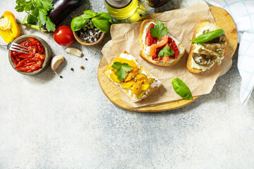 Open sandwiches set with salted salmon, sun dried tomato, grill aubergine, grill bulgarian pepper and cream cheese on a stone table. Healthy food, vegetarian appetizer. View from above. Copy space.