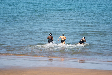Three women take an autumnal dip on the beach