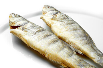 Smoked sea fish in a white plate on a white background. Close-up, selective focus.