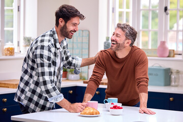 Same Sex Male Couple At Home In Kitchen Having Breakfast Together